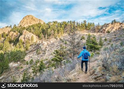 mail hiker with a backpack on a trail to Horsetooth Rock, a landmark of Fort Collins, Colorado, winter scenery without snow