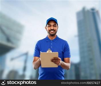 mail service and shipment concept - happy indian delivery man with clipboard in blue uniform over tokyo city skyscrapers background. happy indian delivery man with clipboard in blue
