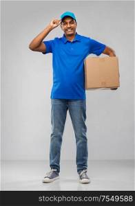 mail service and shipment concept - happy indian delivery man with parcel box in blue uniform over grey background. happy indian delivery man with parcel box in blue