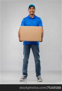 mail service and shipment concept - happy indian delivery man with parcel box in blue uniform over grey background. happy indian delivery man with parcel box in blue