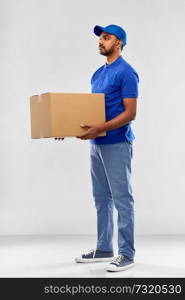 mail service and shipment concept - indian delivery man with parcel box in blue uniform over grey background. indian delivery man with parcel box in blue