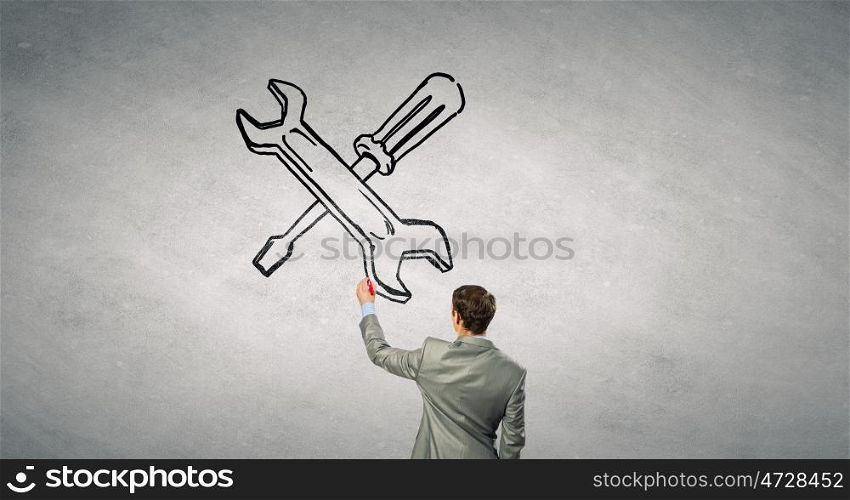Maintenance support. Rear view of businessman drawing tools on wall