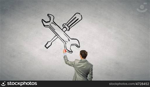 Maintenance support. Rear view of businessman drawing tools on wall