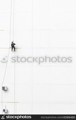 Maintenance worker climbing outside a wall