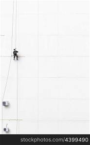 Maintenance worker climbing outside a wall
