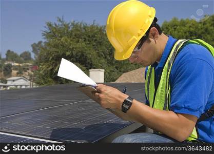 Maintenance worker makes notes with solar array on rooftop Los Angeles California