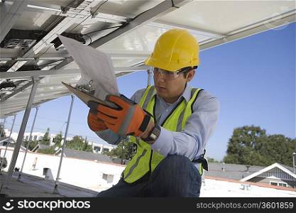 Maintenance worker refers to notes under solar panel in Los Angeles California