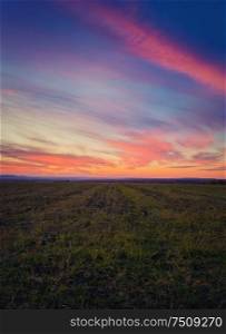 Majestic autumn sunset over a countryside open field. Soft and colorful clouds over empty plain land.