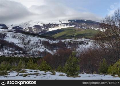 Majestic view of cloudy sky, winter mountain, snowy glade, residential district, conifer and deciduous forest from Plana mountain toward Vitosha mountain, Bulgaria, Europe