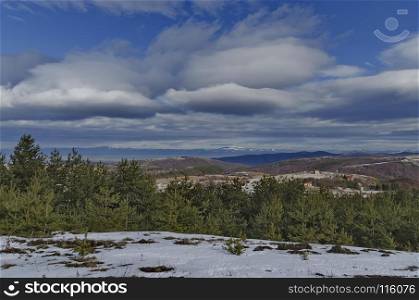 Majestic view of cloudy sky, winter mountain, snowy glade, residential district, conifer and deciduous forest from Plana mountain toward Balkan mountain or Stara planina, Bulgaria, Europe