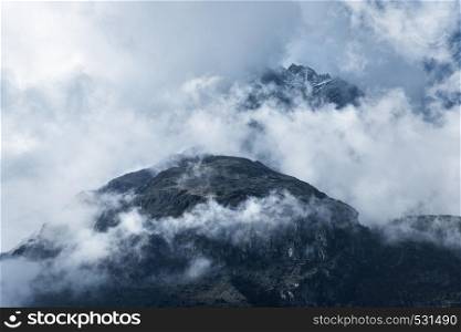 Majestical mountains in clouds in overcast evening in Nepal in summer. Landscape with beautiful high rocks and dramatic cloudy sky. Nature background. Fairy scene. Amazing mountains. Moody scenery