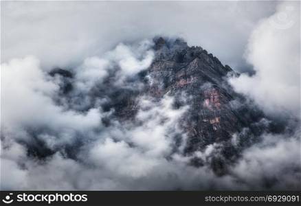 Majestical scene with mountains in clouds in overcast evening in Nepal. Landscape with beautiful high rocks and dramatic cloudy sky at sunset. Nature background. Fairy scene. Amazing mountains at dusk