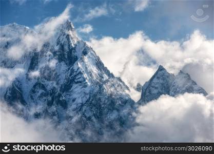 Majestical scene with mountains with snowy peaks in clouds in Nepal. Landscape with beautiful high rocks and dramatic cloudy sky in sunny bright day. Nature background. Vintage. Amazing Himalayas