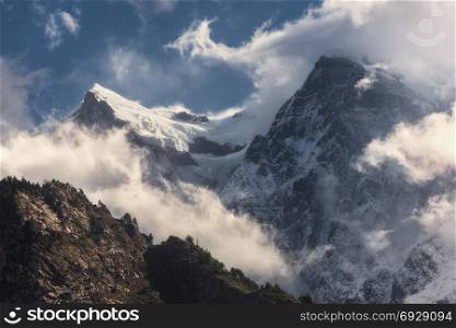 Majestical scene with mountains with snowy peaks in clouds in Nepal. Colorful landscape with beautiful high rocks and dramatic cloudy sky at sunset. Nature background. Fairy scene. Amazing mountains