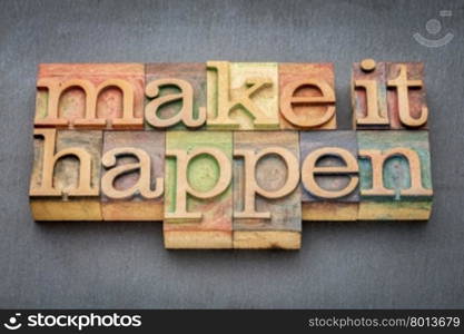 make it happen - inspirational phrase in letterpress wood type printing blocks stained by color inks against slate stone