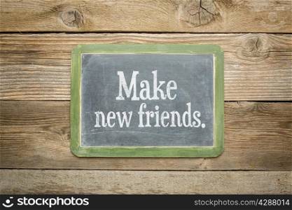 make new friends reminder on a slate blackboard against rustic weathered wood planks