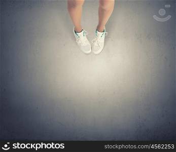 Make next step. Top view of female legs in white sport shoes