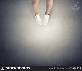 Make next step. Top view of female legs in white sport shoes