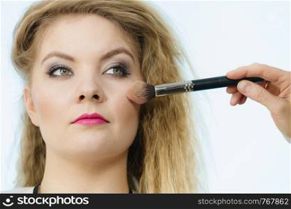 Make up and beauty. Makeup artist applying with brush powder rouge on female check. Makeup artist applying with brush rouge on female check