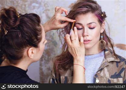Make-up artist and model at work, focus on model's face, close up