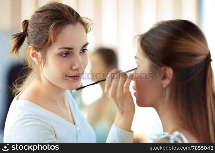 Make-up artist applying eyeshadows with a brush, selective focus on MUA