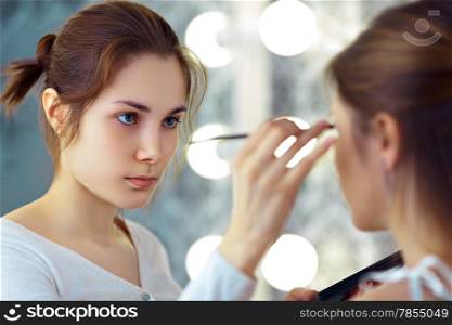 Make-up artist applying eyeshadows with a brush, selective focus on MUA