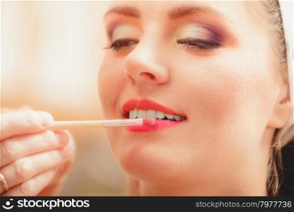 Make up artist applying lipstick with brush.. Make up artist applying lipstick with brush on pretty gorgeous woman lips. Closeup of visagiste and young girl. Beauty and makeup concept.