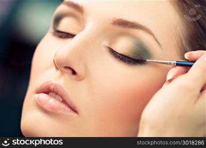 Make-up artist applying liquid eyeliner on model&rsquo;s eyes, close up