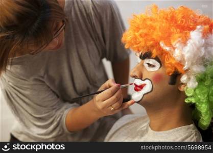 Make up artist applying make up to clown