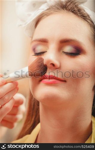 Make up artist applying makeup using brush on pretty gorgeous woman. Closeup of visagiste and young girl. Beauty and makeup concept.. Make up artist visagiste using brush.