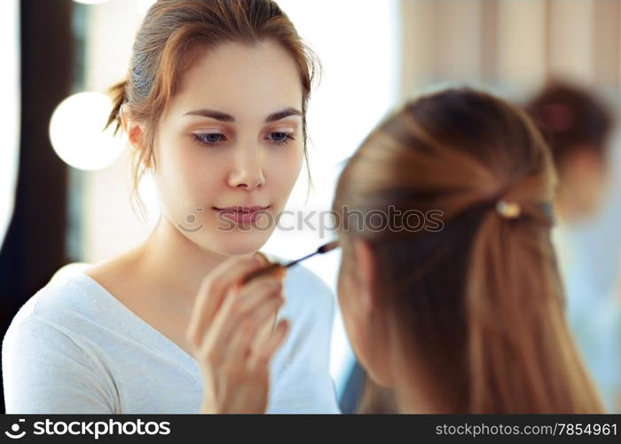 Make-up artist applying mascara on model&rsquo;s eyelashes, selective focus on MUA