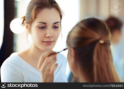 Make-up artist applying mascara on model&rsquo;s eyelashes, selective focus on MUA