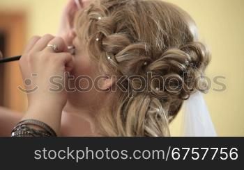 make up artist doing brides make up for her wedding day shot with shallow depth of field