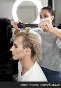 make up man using flat iron his hair