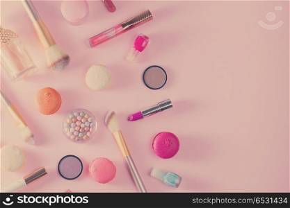 Make up products and macaroons border on pink background, retro toned. Make up products and macaroons. Make up products and macaroons