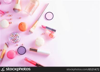 Make up products and macaroons. Make up products and macaroons border on pink flat lay scene