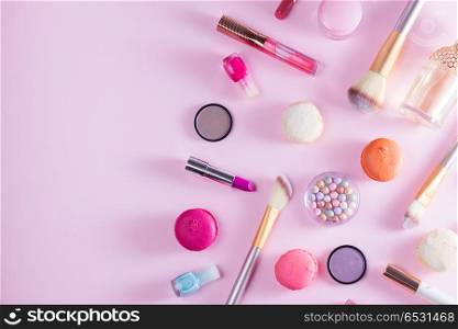Make up products and macaroons. Make up products and macaroons border on pink background