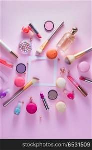 Make up products and macaroons. Make up products and macaroons flat lay frame with copy space on pink background, top view scene