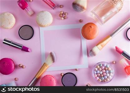 Make up products and macaroons. Make up products and macaroons frame with copy space on pink background