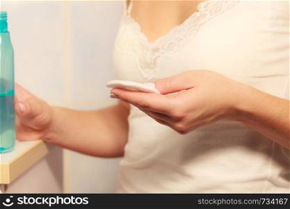 Make up remove skin care. Closeup woman holding cotton swab and makeup remover liquid cosmetic in hands.. Woman with cotton swab cleaning her skin.