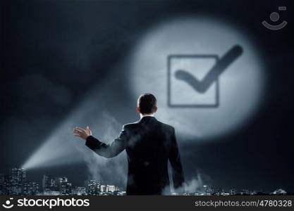 Make your choice. Businessman standing with back and checkbox sign in spotlight