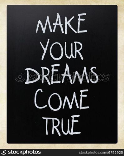 ""Make your dreams come true" handwritten with white chalk on a blackboard"