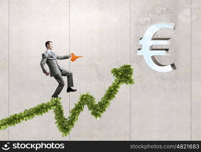 Make your income grow. Young cheerful businessman watering green euro sprout with can