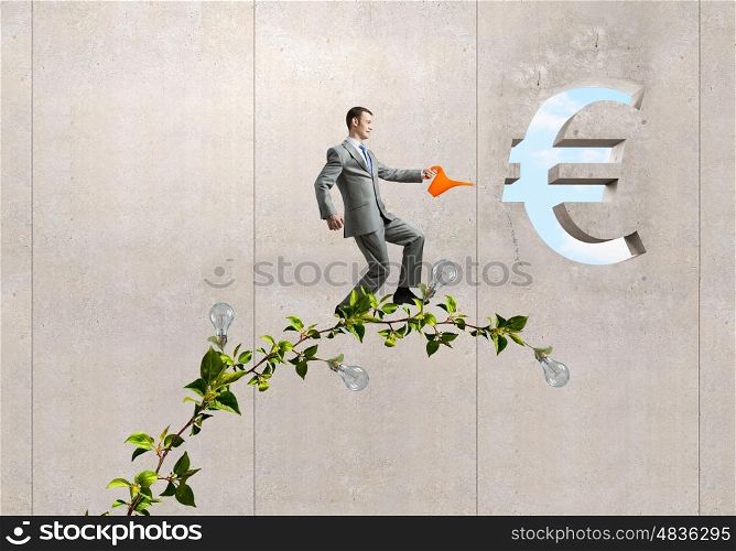 Make your income grow. Young cheerful businessman watering green euro sprout with can