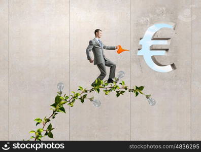 Make your income grow. Young cheerful businessman watering green euro sprout with can