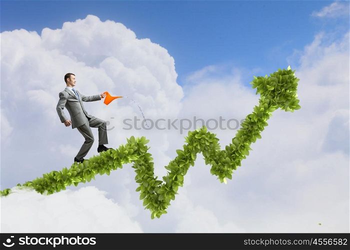 Make your income grow. Young cheerful businessman watering green growing graph with can