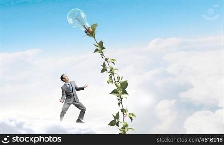 Make your income grow. Young cheerful businessman watering green sprout with can
