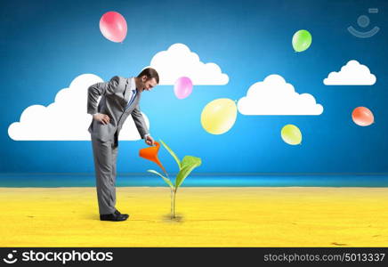 Make your income grow. Young cheerful businessman watering green sprout with can