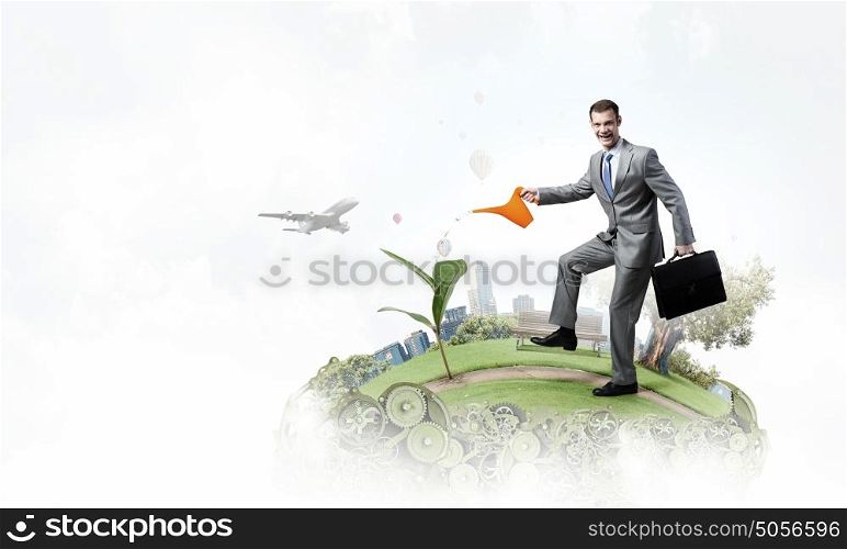 Make your income grow. Young cheerful businessman watering green sprout with can