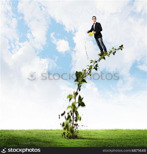 Make your income grow. Young man pouring water on growing tree concept